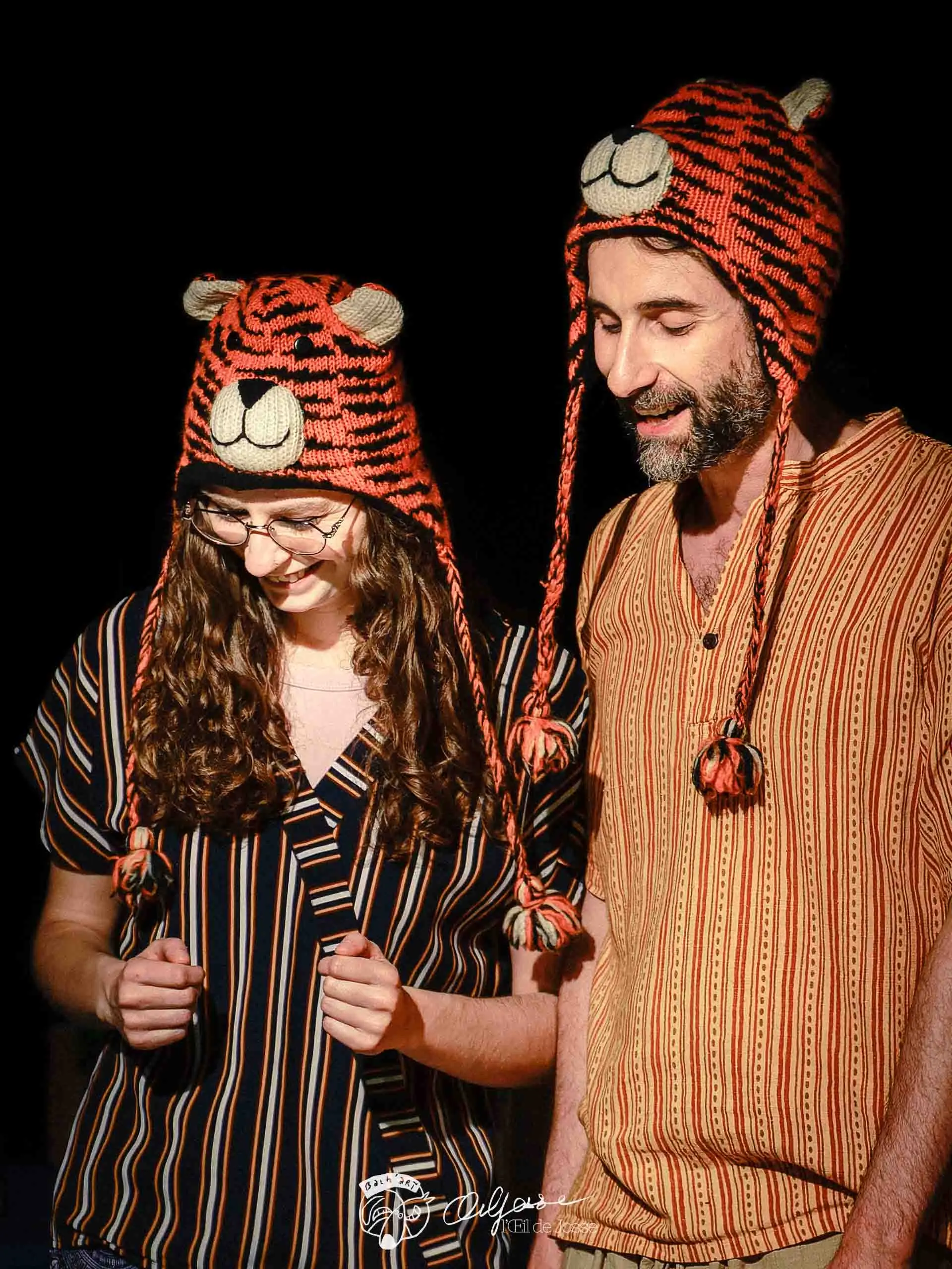 Gros plan sur deux comédien·nes aux bonnets de tigre, l’air ravi.