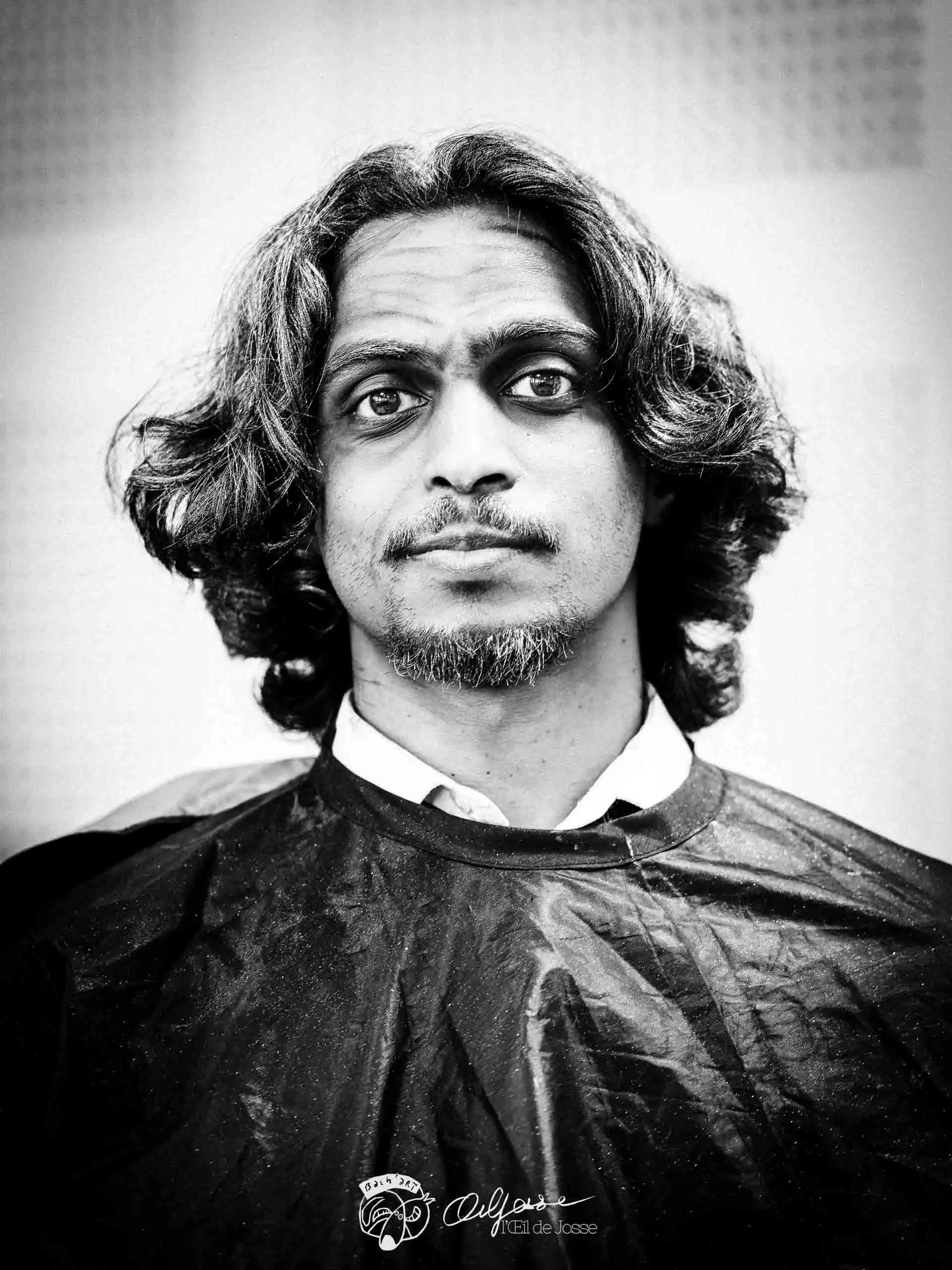 Portrait d’un comédien maquillé, cheveux longs, prêt à entrer en scène.